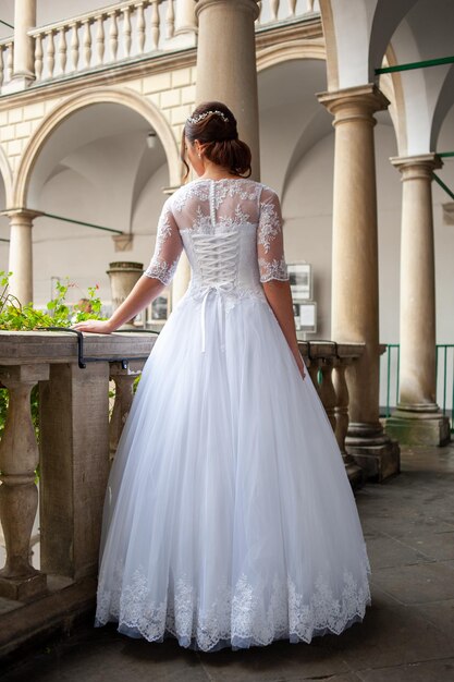 A woman in a white wedding dress stands on a balcony