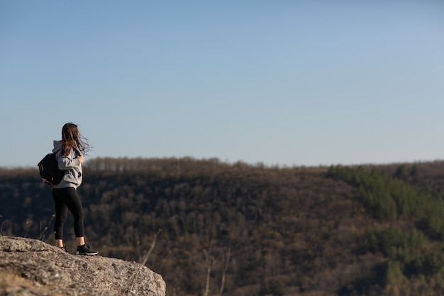 Woman who hikers enjoys a break look at the top of the mountain and pine forest