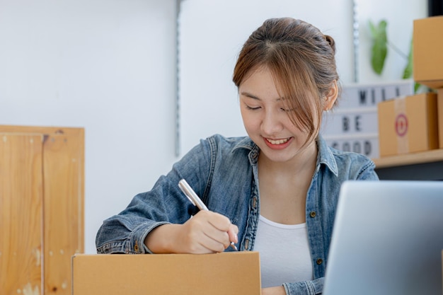 Woman who runs an ecommerce business is writing a list of customers on paper before shipping to them she runs an ecommerce business on websites and social media Concept of selling products online