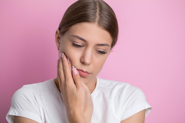 Woman who suffers from a terrible pain in her teeth touching her cheeks with her hand palm