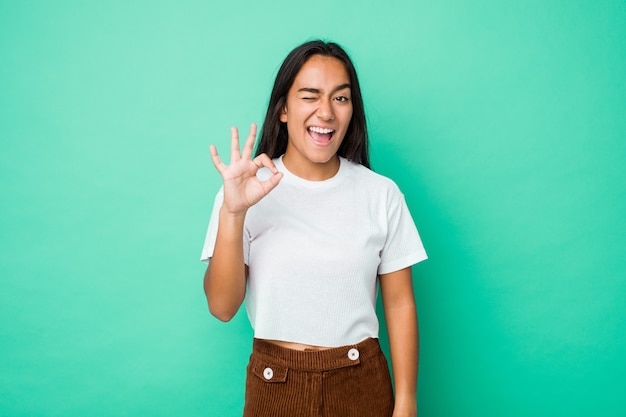 Woman winks an eye and holds an okay gesture