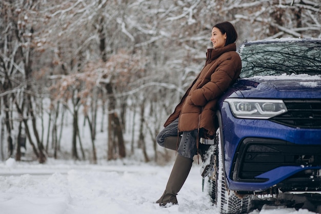 Woman in winter forest by her car