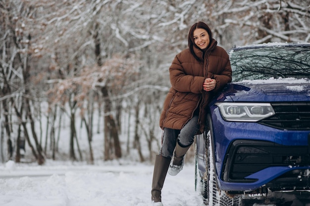 Woman in winter forest by her car