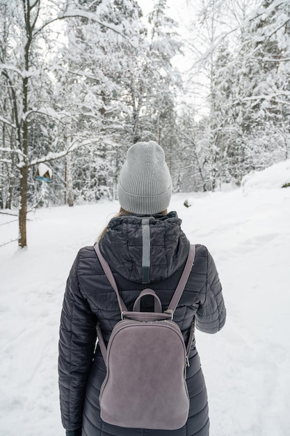 Woman in winter jacket walking in snowy winter forest snowy winter day