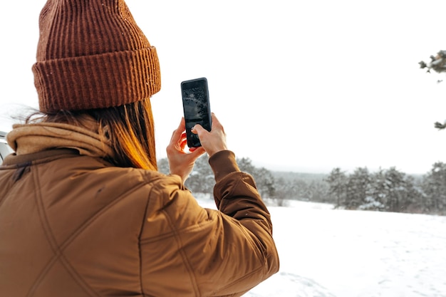 Woman in winter warm jacket walking in snowy winter forest