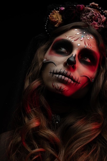 Woman with artistic spooky makeup and fresh flowers on head standing prepared for halloween party