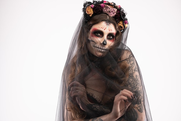 Woman with artistic spooky makeup and fresh flowers on head standing prepared for halloween