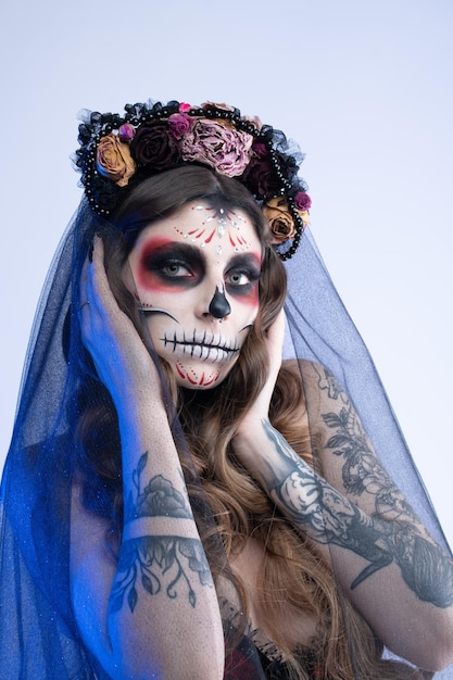 Woman with artistic spooky makeup and fresh flowers on head standing prepared for halloween