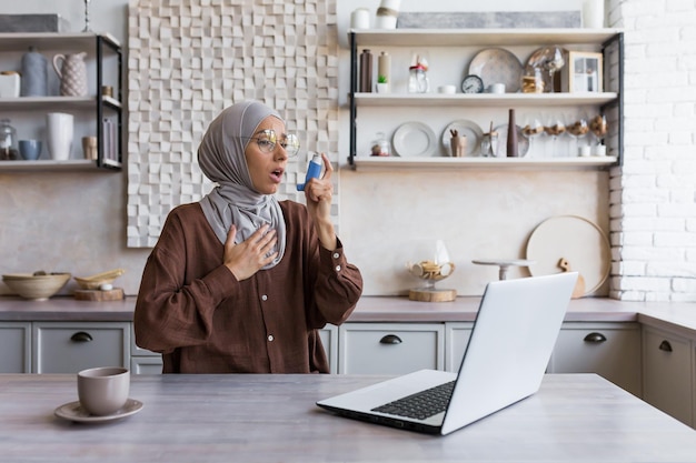 Woman with asthma at home muslim woman in hijab using inhaler to ease breathing housewife working