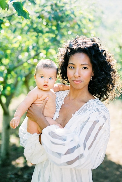 Woman with a baby in her arms in a green garden