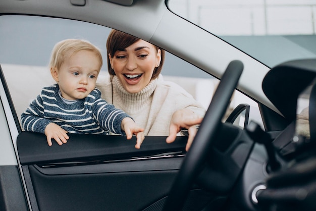 Woman with baby son choosing a car in a car salon