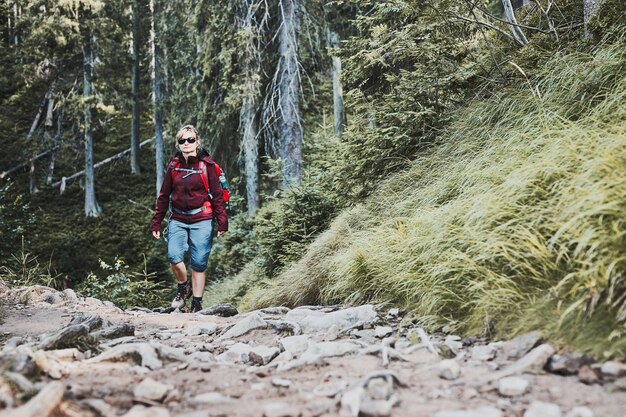 Photo woman with backpack hiking in mountains spending summer vacation close to nature