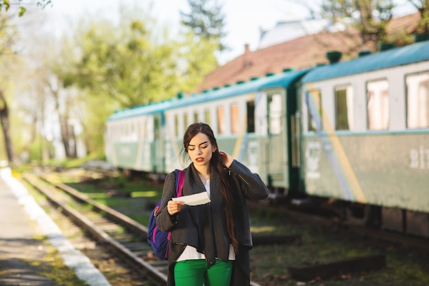 Woman with a backpack, near the train checks his ticket to the station platform