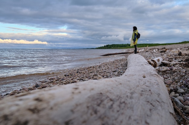 Woman with backpack standing on the riverbank