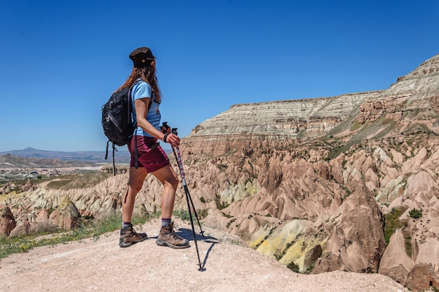 A woman with a backpack stands on a high mountain in Cappadocia and looks at the multicolored rocks Turkey