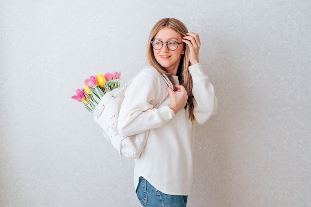 Woman with bag of tulips flowers on white background.