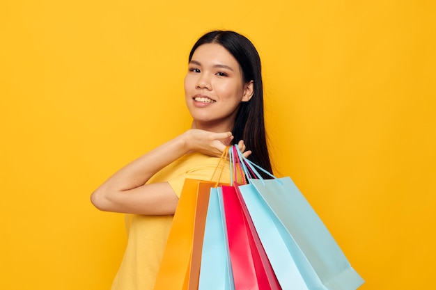 Woman with bags in her hands posing on yellow background