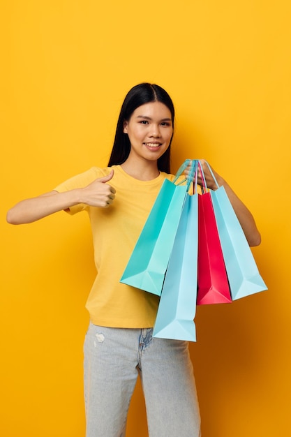 Woman with bags in her hands posing on yellow background