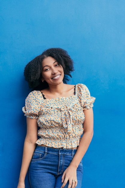 Woman with beautiful Afro hair She is looking at the camera with a smiling expression against a blue background