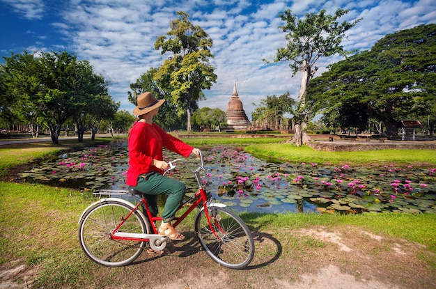 Woman with bicycle near temple in Thailand