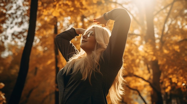 A woman with blonde hair and glasses is stretching her arms in front of a golden autumn forest.