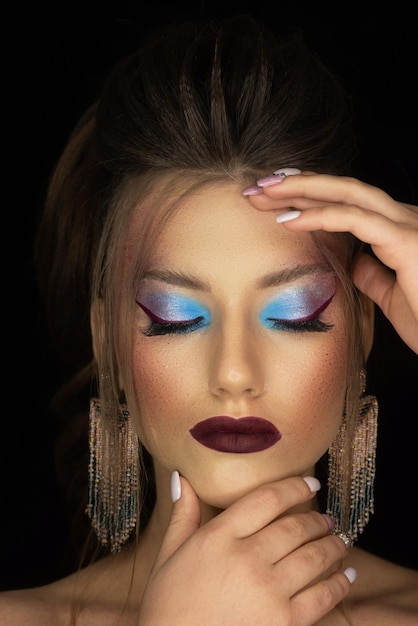 A woman with blue eyes and blue eyes holds her head with her hand on her head