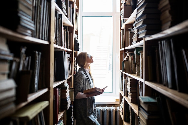 Woman with book looking at bookshelves