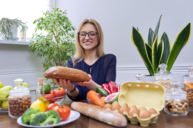 Woman with bread in her hands with food on the table looking at the camera