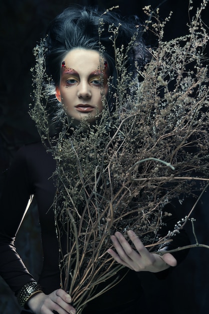 Woman with bright make up and dry branches