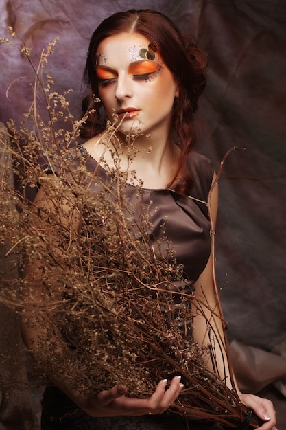 Woman with bright make up with dry branches