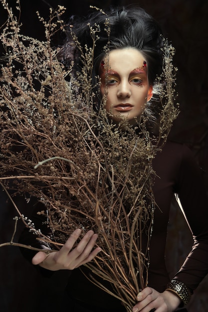 Woman with bright make up with dry branches