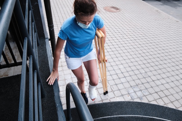 A woman with a broken leg climbs the stairs.