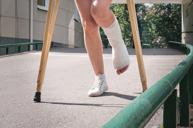 A woman with a broken leg walks down a ramp using orthopedic crutches