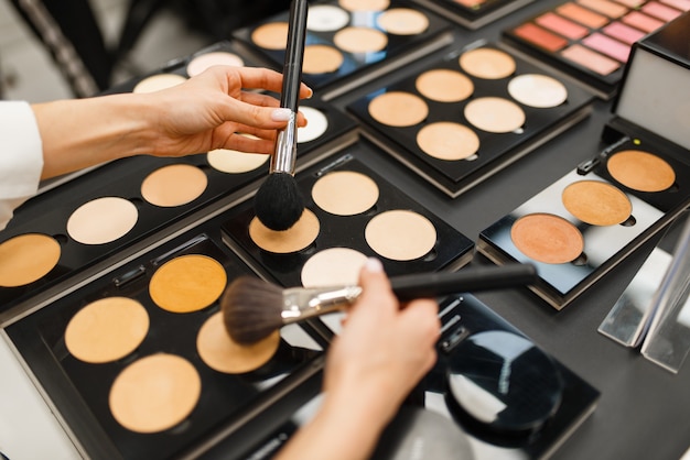 Woman with brush choosing powder tone in cosmetics store. Buyer at the showcase in luxury beauty shop salon, female customer in fashion market