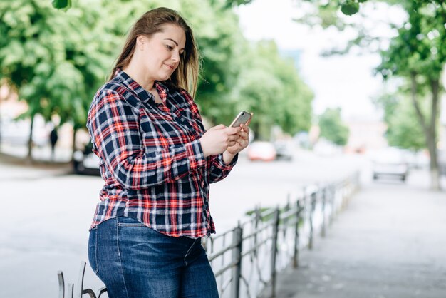 woman with checkered shirt in the park using mobile phone