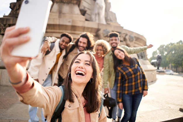 Woman with a cheerful group of college of university campus taking a smiling selfie outdoors