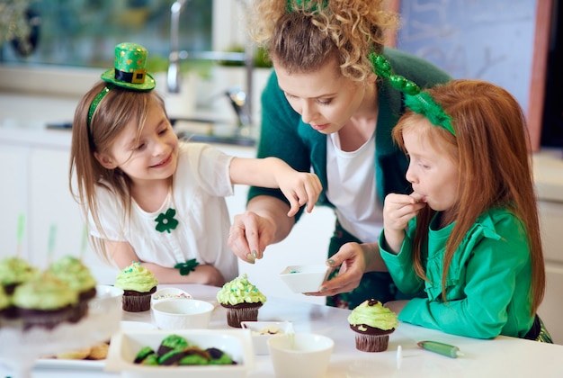 Woman with children decorating cupcakes