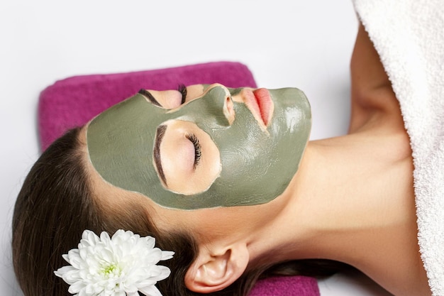 Woman with clay facial mask in beauty spa Skincare Beauty Concept Closeup portrait of beautiful girl