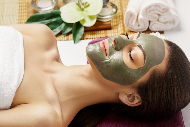 Woman with clay facial mask in beauty spa Skincare Beauty Concept