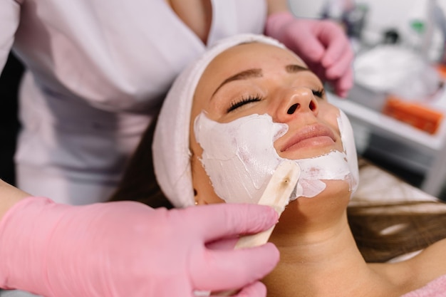 Woman with clay facial mask in beauty spa