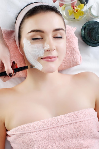 Woman with clay facial mask in beauty spa