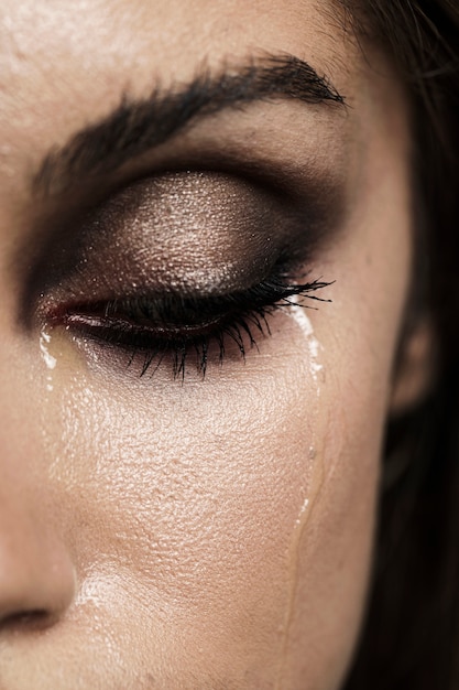 Woman with closed eyes and make-up crying