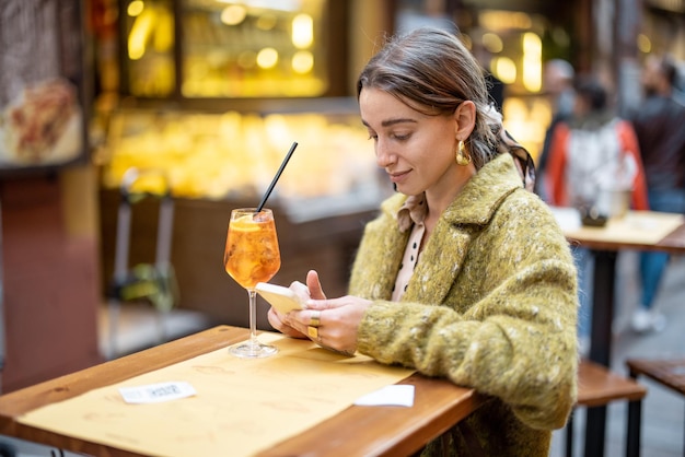 Woman with a cocktail at outdoor bar or restaurant in bologna city