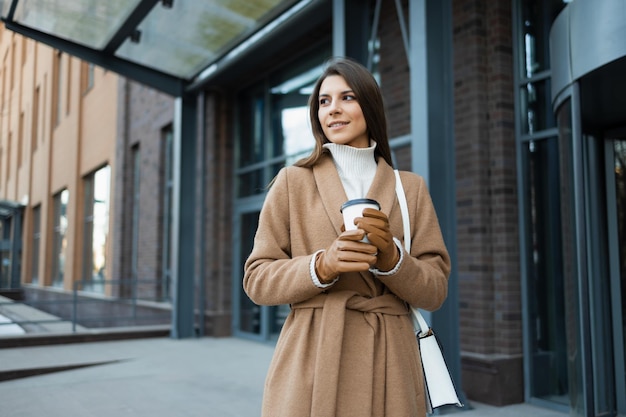 Woman with coffee cup on the background of the building of the business center