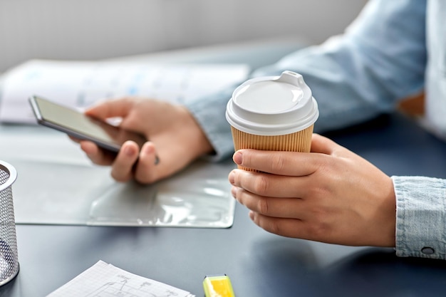 Photo woman with coffee using smartphone at office