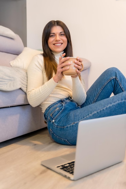 Woman with a computer sitting on a sofa with a hot coffee millennial social media blog