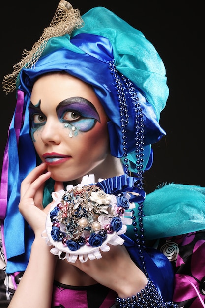 Woman with creative make up holding a bouquet of jewelry