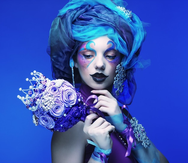 Woman with creative make up holding a bouquet of jewelry