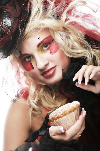 Woman with creative makeup in doll style with cake