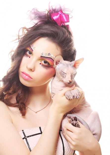 Woman with creative visage holding Sphynx cat